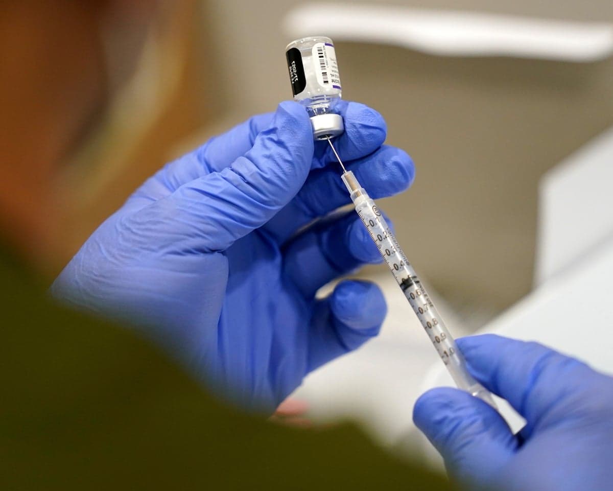 Gloved hands hold a syringe.
