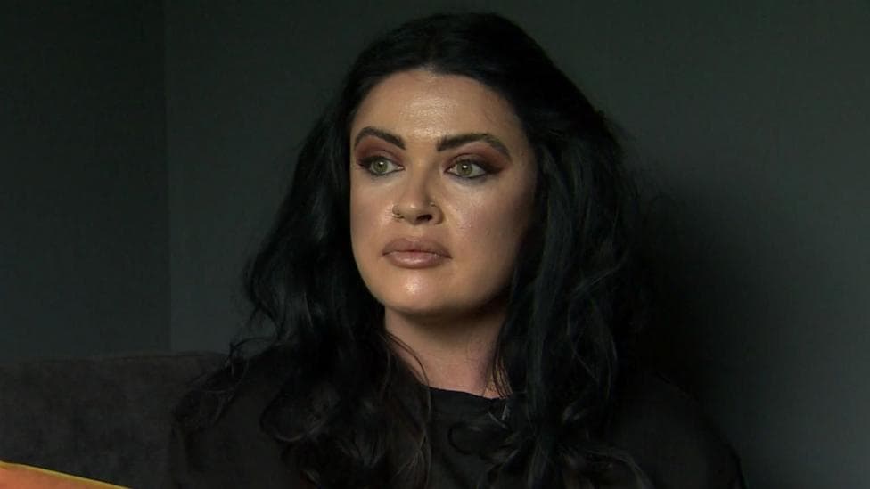 A woman with dark hair looking off to the right, she is wearing a black top